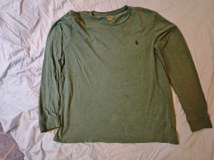 Grön långärmad t-shirt från Polo Ralph Lauren - Snygg grön långärmad t-shirt från Polo Ralph Lauren i bomull. Klassisk rund halsringning och diskret broderad logga på bröstet. Modellen är custom slim fit och passar perfekt till en avslappnad stil. Enstaka små fläckar men dem synns inte så mycket. 