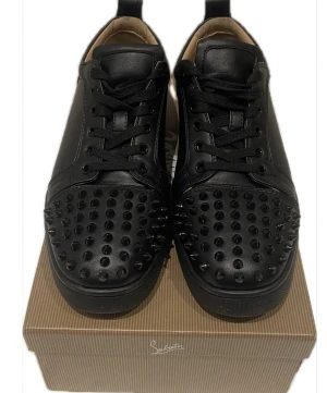Svarta Christian Louboutin sneakers med nitar - Säljer ett par svarta sneakers från Christian Louboutin med coola svarta nitar på tån och klassisk röd sula med logga. Skorna har snörning, rund tå och är tillverkade i skinn. Perfekt för dig som vill sticka ut med en edgy stil.