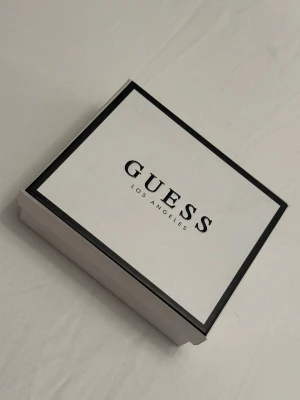 Svart plånbok från Guess med gulddetaljer - Helt ny snygg svart plånbok från Guess med croco-mönstrad yta och stilrena gulddetaljer framtill. 