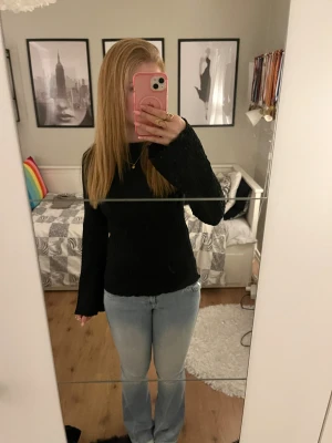 Svart ribbad långärmad tröja - Säljer en svart långärmad tröja med ribbad struktur och rund hals. Tröjan har en slim passform och är tillverkad i mjukt material som sitter skönt mot kroppen. Perfekt att styla med jeans eller kjol för en enkel och snygg look.