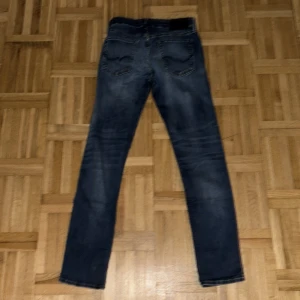 Slim fit jeans från Jack & Jones - Mörkblå slim fit jeans från Jack & Jones, modell Glenn. Klassisk femficksdesign med snygga slitningar och tvättade detaljer. Jeansen har normal midja och raka ben, tillverkade i stretchig denim för skön passform.