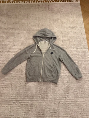 Grå zip hoodie Comme des Garçons Play - Grå zip hoodie från CDG med svart dubbel hjärta, vita snören och två fickor framtill. Mjuk bomullskvalitet och långärmad modell. Svinbra för skolan och passar till allt!! Skicka DM om frågor!!