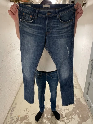 Jack & Jones Slim Glenn jeans blå 31/32 - Snygga Slim Glenn jeans från Jack & Jones i klassisk blå tvätt med slitningar och kontrastsömmar. Modellen har fem fickor, slim passform och raka ben. Perfekt för dig som gillar en modern och stilren look.