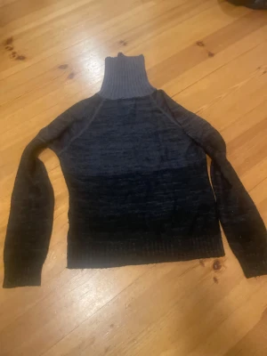 Mörkgrå polotröja från ONLY - Snygg mörkgrå polotröja från ONLY i stickat material. Tröjan har en hög, ribbad polokrage och långa ärmar. Perfekt för dig som gillar en enkel men cool look med lite edge. Passar dig som vill ha något varmt och stilrent till garderoben.