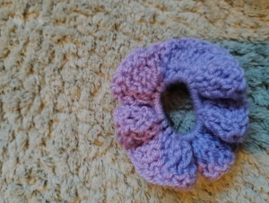 Lila virkad scrunchie  - Superfin handvirkad scrunchie i lila med volangkant. Perfekt för att ge din frisyr en söt och färgglad touch. Mjuk och stretchig, passar både till uppsatt hår och som accessoar runt handleden.
