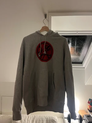 Grå Champion Yankees hoodie - Säljer en grå hoodie från Champion med New York Yankees-logga i rött och svart på bröstet. Tröjan har huva med snörning, stor magficka och långa ärmar med Champion-logga på vänster ärm. 