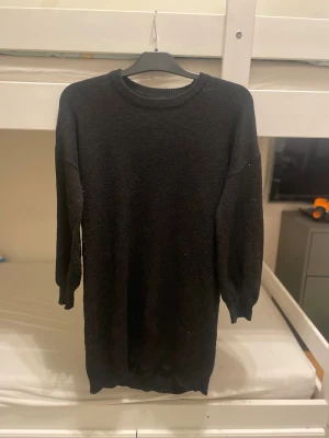 Svart stickad klänning från Bik Bok - Svart stickad klänning från Bik Bok i storlek XS. Klänningen har rund hals, lång arm och är tillverkad i en mjuk ullblandning. Enkel och stilren design som är perfekt för dig som gillar en klassisk look med cozy vibes.