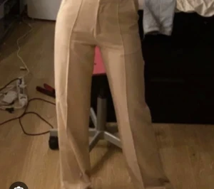 Beiga kostymbyxor från Madlady 36/tall - Snygga beiga kostymbyxor från Madlady med hög midja och raka ben. Byxorna har pressveck framtill och hällor för bälte. Perfekta för en clean och stilren look. Materialet känns mjukt och har en lätt stretch för extra komfort.