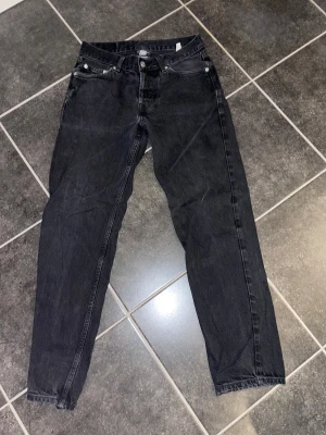 Svarta jeans från Sweet SKTBS - Svarta jeans från Sweet SKTBS med klassisk femficksdesign och rak passform. Jeansen har en snygg mörk tvätt och är tillverkade i slitstarkt bomullsmaterial. Märkespatch baktill i midjan och metallknappar framtill ger en cool streetkänsla.