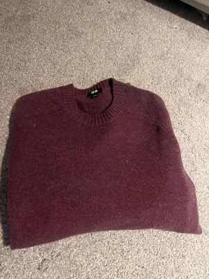 Vinröd kashmirtröja från Uniqlo - Mysig vinröd tröja från Uniqlo i mjuk kashmir. Klassisk rund halsringning med ribbade muddar och enkel, stilren design. Perfekt för lager på lager under kyliga dagar.