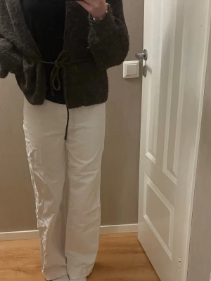 Vita vida byxor i bomull - Säljer ett par vita byxor med bred passform och raka ben. Byxorna har en klassisk femficksdesign och är tillverkade i mjukt bomullstyg. Perfekta för en clean och avslappnad look. Passar dig som gillar loose fit och enkel stil.