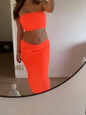 Orange bandeau tubtopp - Säljer en snygg orange bandeau tubtopp som är axelbandslös och croppad. Toppen har en enkel och stilren design med elastisk passform som sitter bekvämt över bröstet. Perfekt för sommarens varma dagar och festivaler.