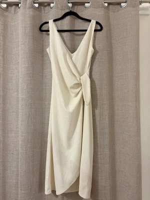 Omlottklänning från H&M - Klänning i krämvit/krämbeige färg i storlek XS. Från H&M. Sparsamt använd, i mycket fint skick.