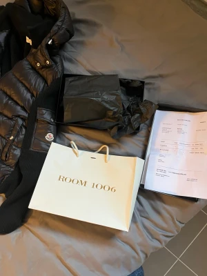 Svart cardigan med huva från Moncler med kvitto - Säljer en svart cardigan från Moncler med huva och ribbstickade ärmar. Västen har en quiltad framsida, dragkedja och en ficka med Moncler-logga på ärmen. Perfekt för dig som vill ha en snygg och varm look under höst och vinter. Tilkommer Kvitto!! Köpt på Room