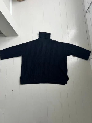 Svart stickad ribbad polotröja från H&M - Mysig svart polotröja från H&M i storlek XL. Tröjan är ribbstickad med hög polokrage och har en loose fit som ger en chill vibe. Perfekt för lager på lager under höst och vinter. Passar dig som gillar enkel men stilren look.