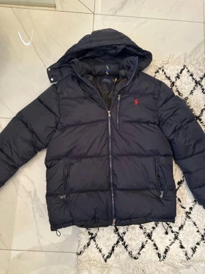Navy Ralph Lauren puffer  - Säljer en mörkblå jacka ifrån polo Ralph lauren | Skick 10/10 aldrig använd tagsen medföljer. Köpte den men sedan använde jag aldrig den eftersom jag hade en annan jacka. Pris 1999kr, såklart diskuterbart vid en snabb affär |Storlek M | Färg: mörkblå | Vid frågor eller funderingar är det bara att skriva | Mvh Etienne 🤙