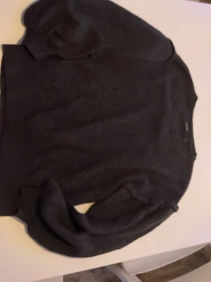 Svart stickad tröja med rund hals - En svart stickad tröja med rund hals och puffärmar. Perfekt basplagg till garderoben och funkar året runt. Tröjan har en klassisk passform och är mjuk i materialet.