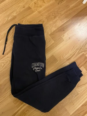 Mjukisbyxor från Champion - Säljer ett par mörkblå lågmidjade mjukisbyxor från Champion med broderad logga och text på ena benet. Strl M