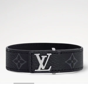 LV Slim armband - Stilrent svart armband från Louis Vuitton i läder med silverfärgat LV-logo framtill. Armbandet har diskreta monogramdetaljer och en smal, elegant design som passar till många olika stilar. Självklart äkta