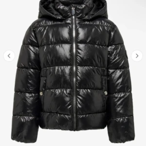 Svart pufferjacka från ONLY - Säljer en svart pufferjacka från ONLY med huva och dragkedja framtill. Jackan har quiltad design, två fickor med tryckknappar och en snygg logga på ärmen. Perfekt för kyliga dagar och riktigt skön att bära. Känns som en xs