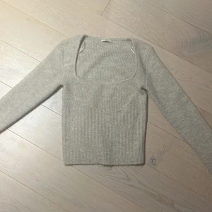 Grå ribbad stickad tröja från Gina - Superfin ljusgrå stickad tröja från Gina Tricot med ribbat tyg och fyrkantig urringning. Den är i storlek S. Tröjan har använts ett fåtal gånger men har knappast några tecken på användning. 