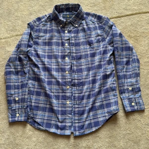 Blårutig skjorta från Ralph Lauren - Snygg blårutig skjorta från Ralph Lauren Performance med klassisk button-down krage och broderad logga på bröstet. Skjortan har vita knappar och lång ärm, perfekt för dig som gillar stilren och tidlös design. Materialet är mjuk bomull som känns skönt mot huden.