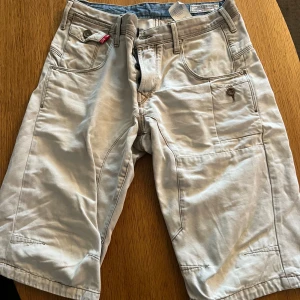 Beiga shorts från Jack & Jones - Säljer ett par beiga shorts från Jack & Jones, modell Stan Osaka Knickers. De har flera fickor, knappdetaljer och klassisk passform. Perfekta för sommardagar och har en snygg, enkel look med diskreta sömmar.