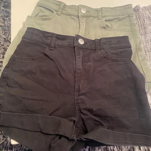 Svarta och gröna shorts från H&M - Två par shorts från H&M, ett par svarta och ett par olivgröna. Båda är högmidjade med klassisk femficksdesign, knapp och dragkedja framtill samt uppvikta benslut. Materialet är mjuk bomull med lite stretch för skön passform. Perfekta för varma dagar och chill stil.