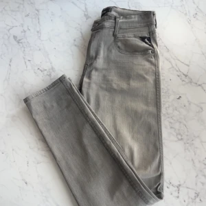 Replay Anbass grå slim jeans - Snygga grå jeans från Replay i modellen Anbass med slim fit. Byxorna är tillverkade i Replay Hyperflex-material som ger extra stretch och komfort. Knappast använda och säljer då de inte kommer till någon användning. Kom gärna med prisförslag! Storlek W30 L32