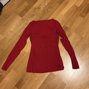 Röd långärmad topp - En enkel och stilren röd långärmad topp med rund hals. Modellen är figurnära och passar perfekt till jeans eller kjol. Tunn och mjuk i materialet, vilket gör den skön att bära hela dagen.