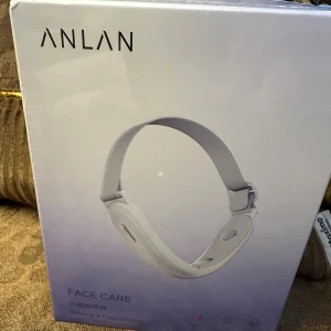 ANLAN Shining V Face Device - ANLAN Shining V Face Device är en elektrisk ansiktsmassager fört V-formad ansiktslyftning. Produkten är ny i oöppnad förpackning och erbjuder flera funktioner för ansiktsvård. Laddningstid ca 3 timmar, vikt 142g. Perfekt för daglig hudvård.