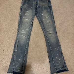 Flared Lorenzo jeans  - Säljer ett par flared ljusblå jeans från Lorenzo med coola slitningar och färgstänk. Jeansen har raka ben med lätt bootcut och klassisk. Säljer för dom va för små, knappast använda👍
