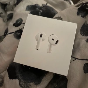AirPods 4 - Snygga och moderna Apple AirPods 4 i originalförpackning. Trådlösa hörlurar med laddningsetui, kompatibla med USB-C. Produkten är i mycket gott skick, med komplett innehåll och inga synliga defekter. Perfekt för musik, samtal och smidig anslutning till Apple-enheter. Köpta september 2025. 