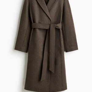 Brun kappa med knytkärp  - Stilren brun kappa i klassisk modell med knytskärp i midjan och bred krage. Jackan är lång och har raka ärmar, perfekt för kyliga dagar. Materialet är mjuk ullmix som ger en lyxig känsla och snyggt fall. Detta är en kappa från H&M som jag köpte för ungefär 2 veckor sen, den är använd 2 gånger sen hitta jag en nanna kappa jag ville ha som kändes mer som mig därför är de onödigt att bara ha skänkt pengar på en kappa jag inte kommer att använda, så de är inget fel på kappan i sig, i helt nytt skick