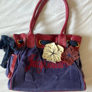 Juicy Couture väska  - Superfin juicy couture väska i lila och röd färg med blommor som dekoration🫶🏼 I fint skick! Rymmer ca ett A4 papper. Köpt på Vinted men var inte riktigt min färg. !Tyvärr inte en äkta juicy couture väska‼️(Men väldigt lik originalet och fin ända!) 