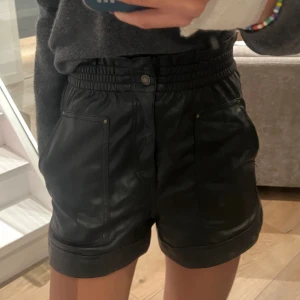 Svarta högmidjade skinnshorts Zara - Säljer ett par svarta högmidjade shorts från Zara i snyggt skinnimitation. De har bred resår i midjan, stora fickor framtill och uppvikta benslut. Strl 38 🫶🏻