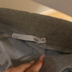 Grå mjukisbyxor med snörning XS - Snygga grå mjukisbyxor i storlek XS med bekväm resårmidja och snörning. Byxorna har en klassisk rak passform och är gjorda i mjukt bomullsmaterial, perfekta för chill dagar eller träning. Enkla att matcha med hoodies eller t-shirts.