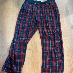 Rödblå rutiga mjukisbyxor  - Säljer ett par sköna mjukisbyxor i rödblått rutigt mönster. Byxorna har resår och snörning i midjan för extra komfort. Perfekta för chill dagar hemma. Materialet känns mjukt och luftigt.