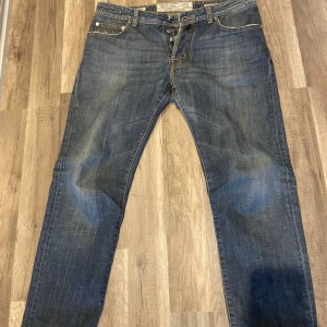 Blå jeans från Jacob Cohën - Snygga blå jeans från Jacob Cohën, handgjorda i Veneto, Italien. Klassisk femficksmodell med kontrastsömmar och läderpatch bak. Jeansen har rak passform. Storlek 34. Relativt bra skick. 7/10