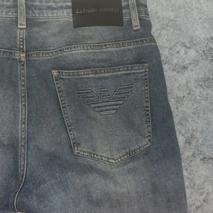 Blå jeans från Emporio Armani - Snygga blå jeans från Emporio Armani med klassisk femficksdesign och broderad logga på bakfickan. Jeansen har en rak passform och är tillverkade i mjukt denimtyg. Perfekta för en chill och stilren look.
