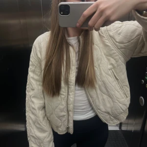 Beige quiltad jacka - Quiltad beige bomberjacka från Mango med vågigt mönster i sömmarna. Jackan har dragkedja framtill, elastiskt band fram och baktill, även framfickor. Felfri och i gott skick! Köpt härifrån, passade inte mig helt så därför jag säljer 💕