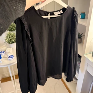 Svart blus med volangdetaljer från Vero Moda - Säljer en svart blus från Vero Moda! Jätte fin till allt. Aldrig använd! 🩷