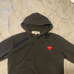 Svart hoodie Comme des Garçons Play - Säljer nu en CDG play hoodie i perfekt skick, inga defekter. Köptes på NK för 2400kr. Passar S och M. Ge ett prisförslag så får vi se!