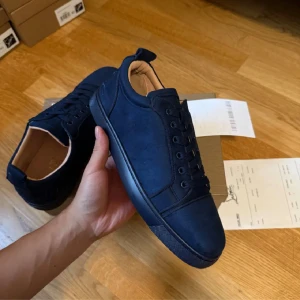 Mörkblå sneakers från Christian Louboutin - Snygga mörkblå sneakers från Christian Louboutin med lyxig mocka och klassisk röd sula med logotyp. Storlek 44 