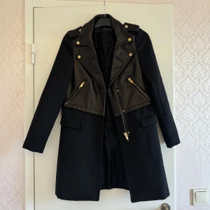 Svart Jacka med Skinnpanel Zara - Svart jacka från Zara Basic med coola detaljer i svart skinn på överdelen och guldiga knappar. Jackan har långa ärmar, två fickor med lock och dragkedjor framtill. Med tanke på att Zara plagg kostar en del så är detta ett pris du INTE vill missa 🤭