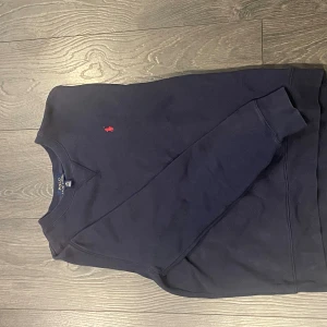 Mörkblå sweatshirt från Polo Ralph Lauren - Klassisk mörkblå sweatshirt från Polo Ralph Lauren. Storlek 14-16 men sitter som en xs. Säljer eftersom den inte passade. 
