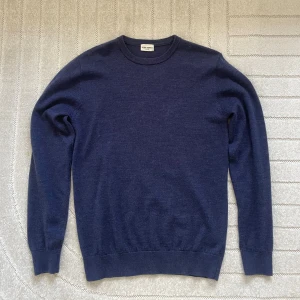 Mörkblå ulltröja från John Henric - Säljer en stilren mörkblå rundhalsad tröja från John Henric. Tröjan är i mjuk merinoull, har lång ärm och ribbade muddar vid ärmslut och nederkant. Perfekt för lager-på-lager och passar till både jeans och chinos.