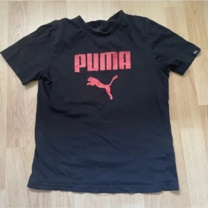 Svart Puma t-shirt  - Svart t-shirt från Puma med stor röd logga och puma-tryck på bröstet. 