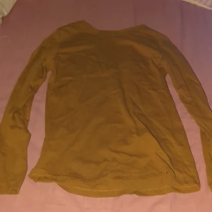 Brun långärmad basictröja H&M - En enkel och stilren brun långärmad tröja från H&M Basic. Tröjan har rund halsringning och är gjord i mjuk bomull, perfekt för lager-på-lager eller som den är. Passar dig som gillar en clean och avslappnad look.