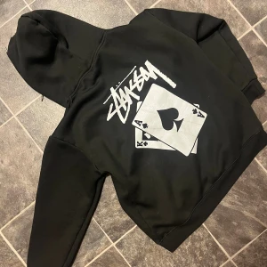  Stüssy hoddie archive  - Svart archive hoddie från stüssy med en fet logga där bak som lockar benätsen fram sida feta långa snören på sidan på tröjan en mindre loga skriv för mer bilder eller nåt 😋